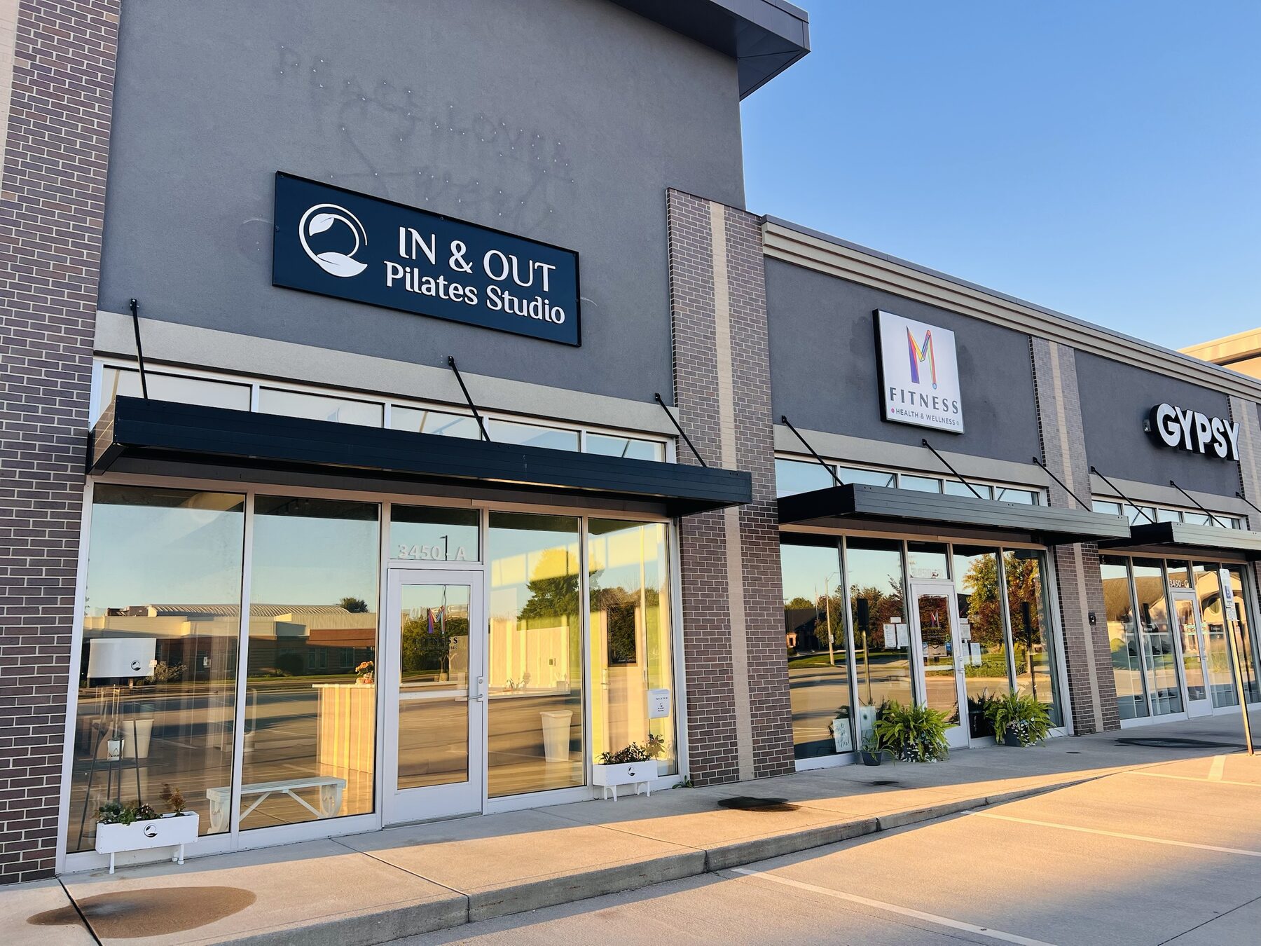 The IN & OUT Pilates Studio storefront: a navy sign above a glass front with a black awning