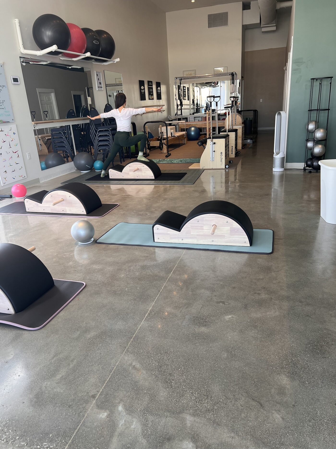 The new IN & OUT Pilates studio: Euna stretching on a spine corrector with more spine correctors on mats in front and the reformers, chairs and Cadillac behind her